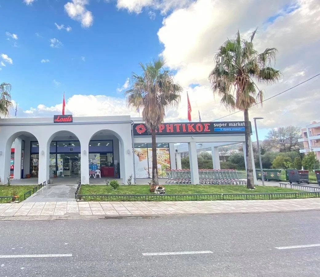 Louis Supermarkets Kritikos store exterior with white arches and palm trees in Kos